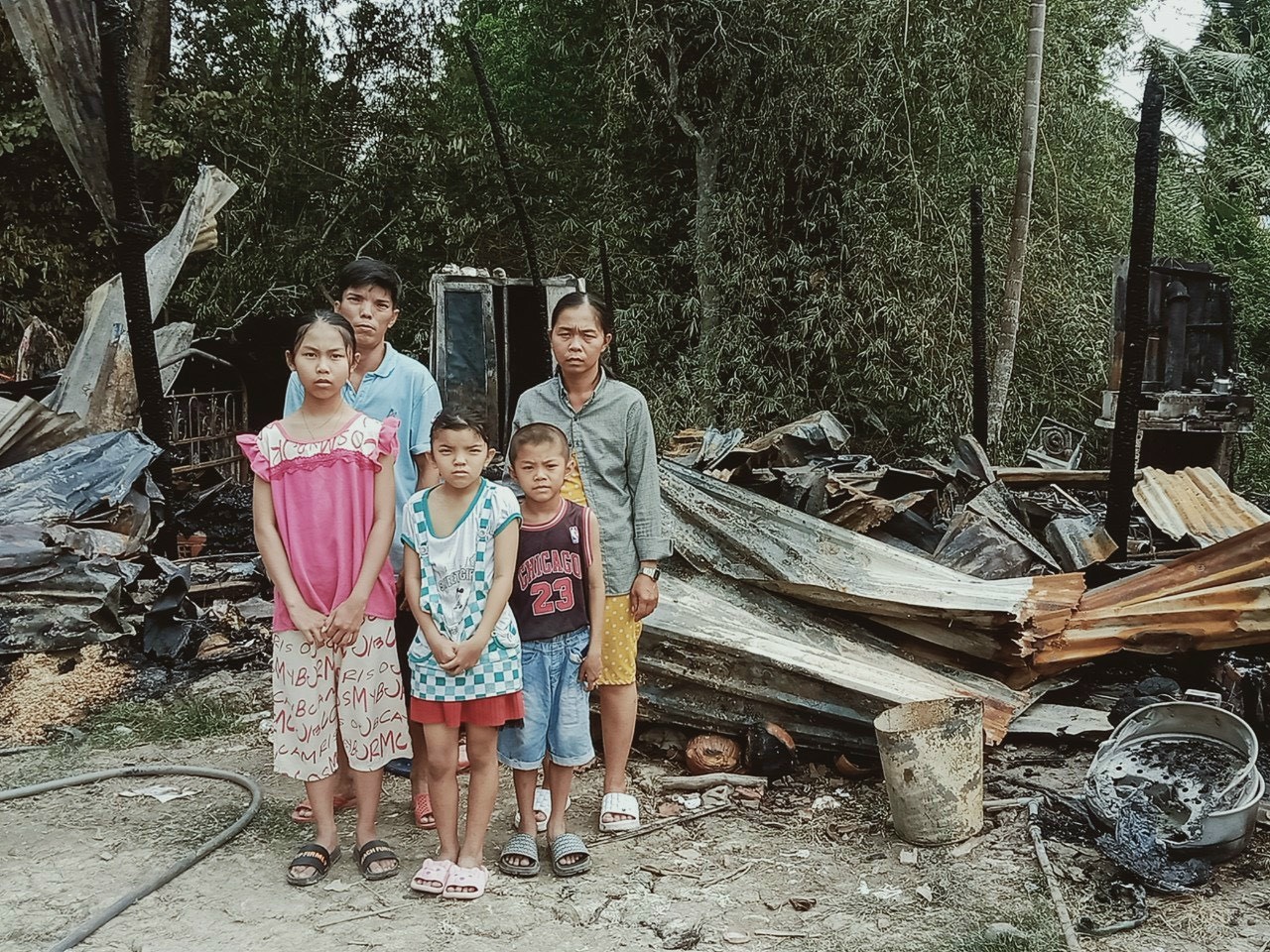 Gia đình anh Mai Hữu Toàn trước căn nhà bị thiêu cháy 
